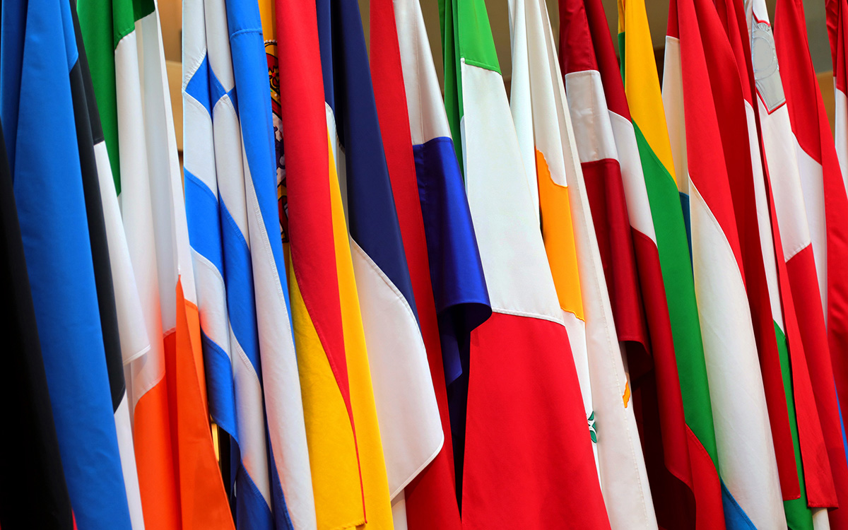 A close-up view of multiple international flags with various colors and patterns displayed side by side. A close-up view of multiple international flags with various colors and patterns displayed side by side.