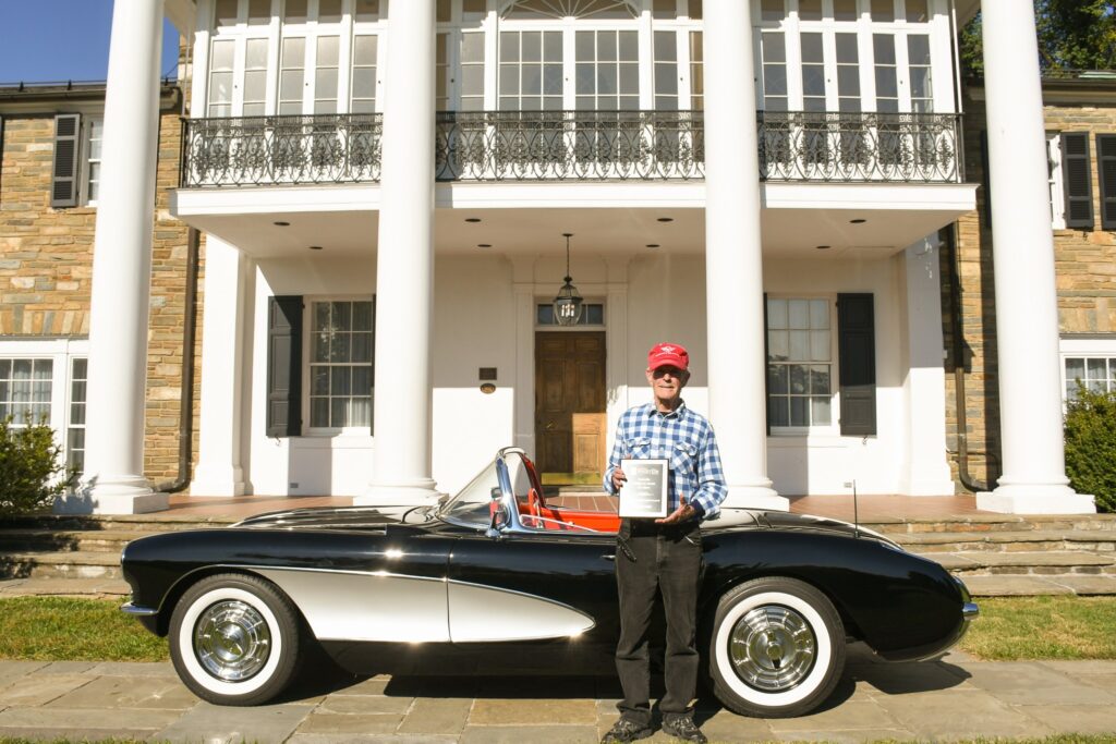 Cal Milans standing with his 1957 Chevrolet Corvette in front of the Glenview Mansion