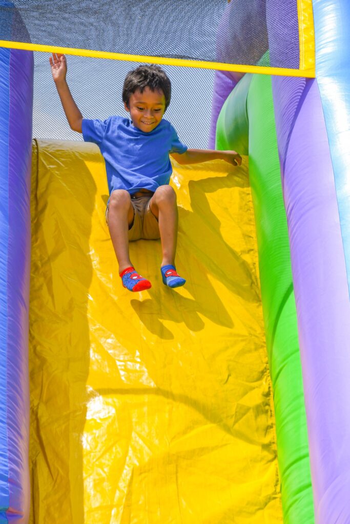 A child smiles as he slides down a blow up slide