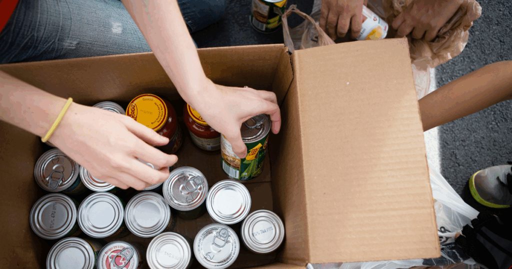 People putting cans of food into a box