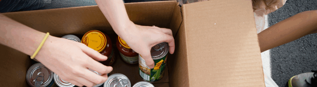 People putting cans of food into a box