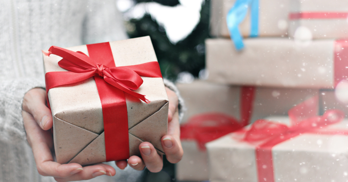 Person holding a holiday gift with a red bow.