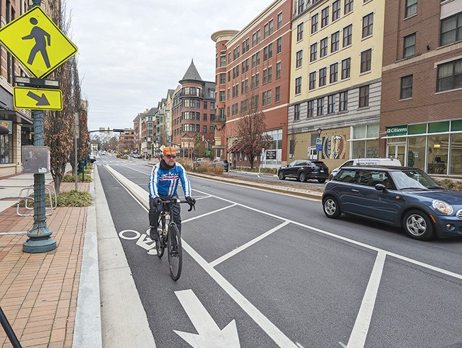 A man riding a bike in a bike lane in Rockville Town Center