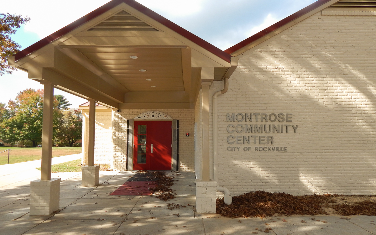 Exterior view of Montrose Community Center in Rockville, featuring a red door, beige brick walls, and the building name displayed on the wall.