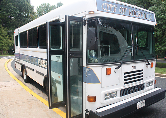 A white City of Rockville bus labeled "307" is parked at a curb with its doors open.