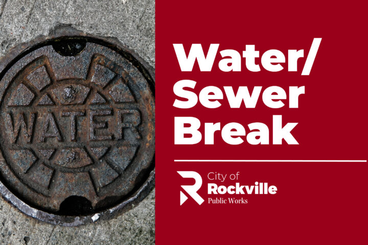 Water utility cover on pavement next to a red banner with white text stating 