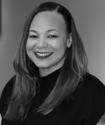 A woman with straight, shoulder-length hair and a side part is smiling, wearing a dark top, in a black-and-white portrait.