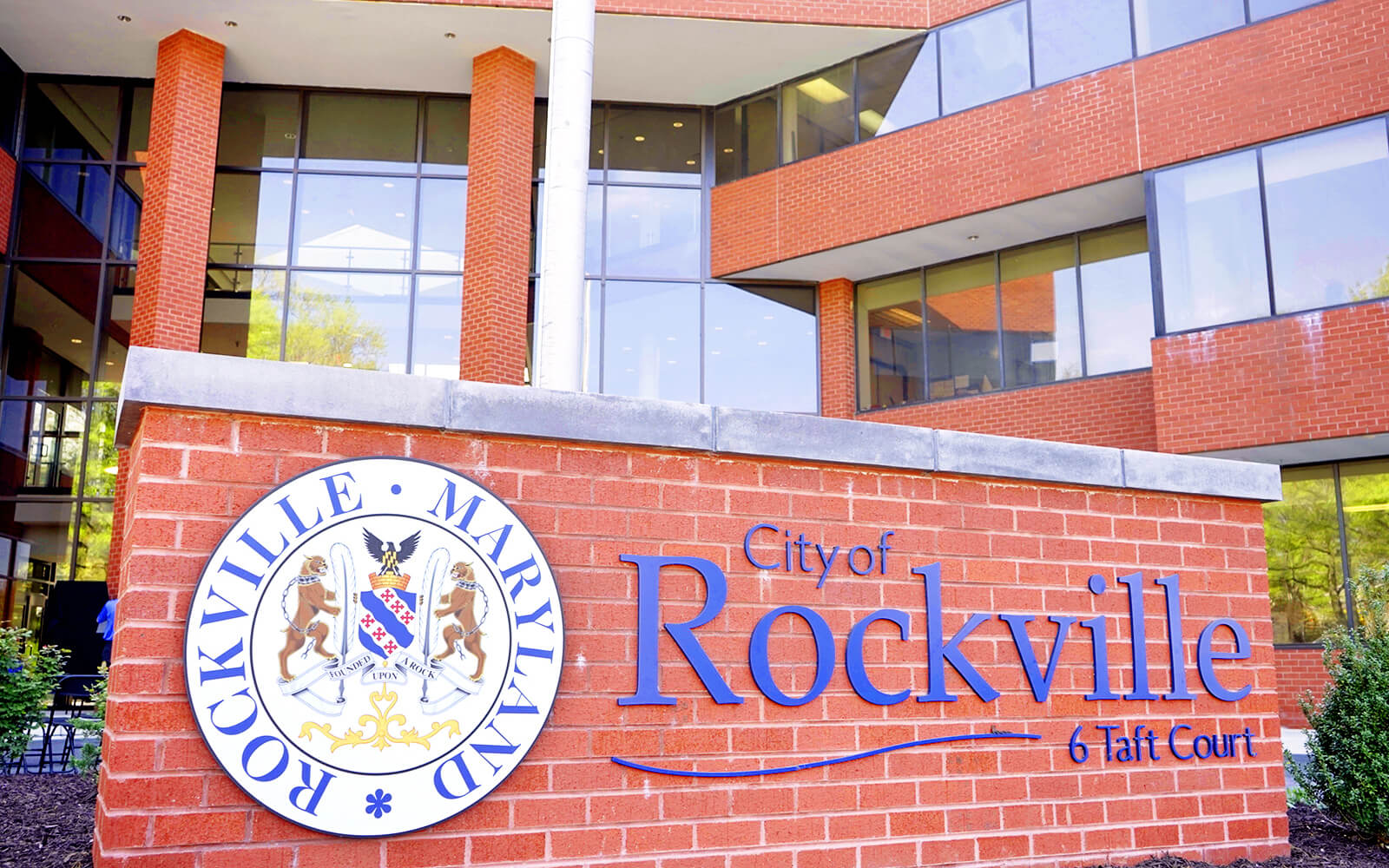 Exterior view of the City of Rockville, Maryland municipal building with a large sign displaying the city name and emblem in front.