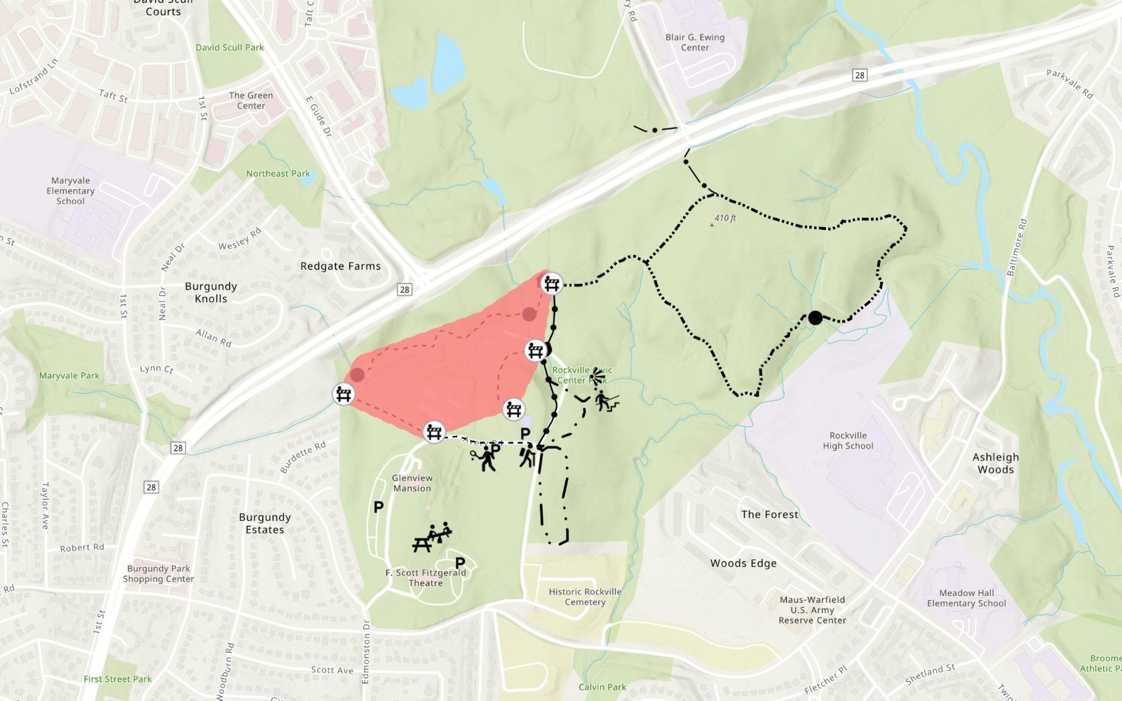 Map showing a highlighted red area in Rock Creek Park with several icons indicating points of interest and dashed lines marking trails. Surrounding neighborhoods and roads are also visible.