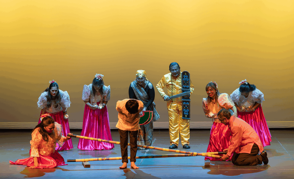 Performers in traditional Filipino clothing participating in a Tinikling bamboo dance.