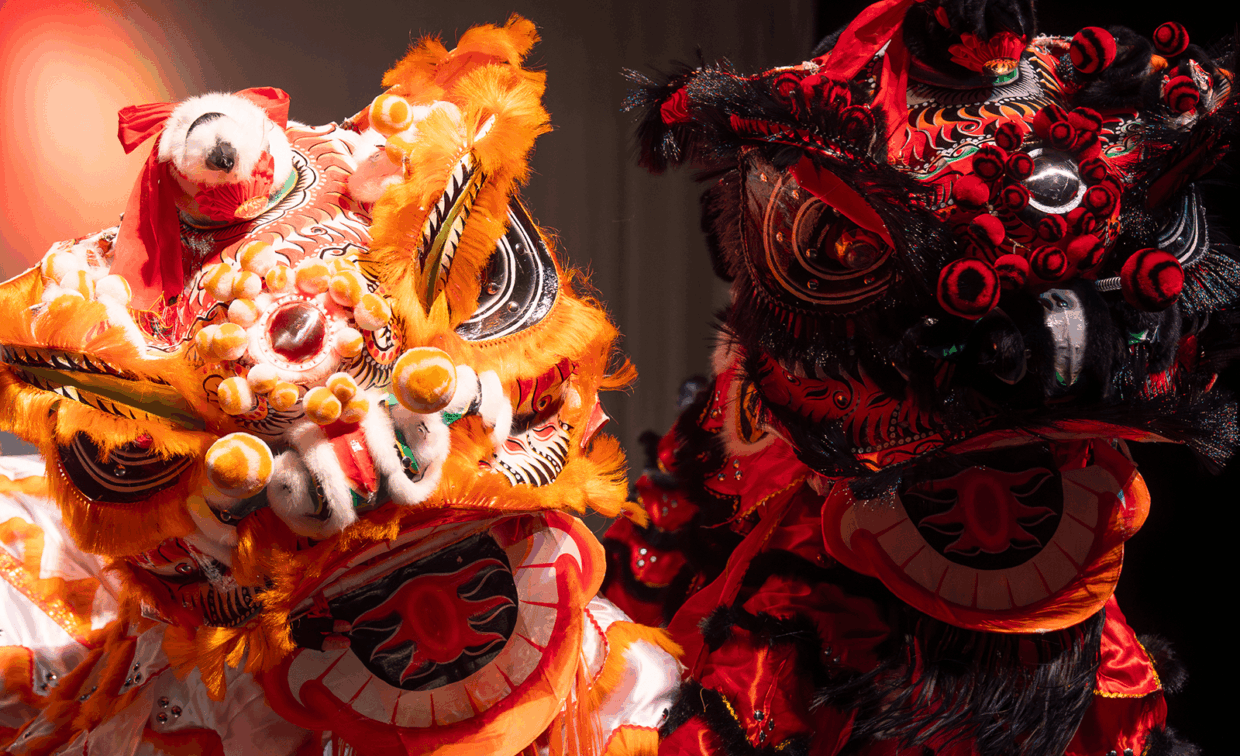 Two ornate lion dance costumes in orange and red.
